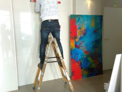 איש מרכיב ציור צבעוני בלובי בניין עומד על סולם